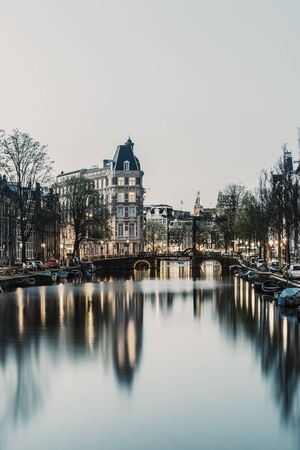 Evening landscape with houses and canal in Amsterdam, twilight and reflection in water, cityscape. Retro stylization, vintage film filterの写真素材