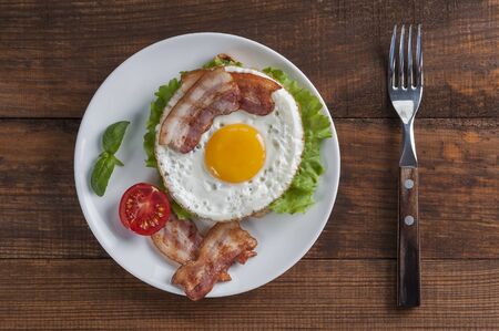 Fried eggs with bacon and vegetables, breakfast on wooden rustic boards, food backgroundの写真素材