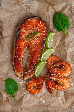 Fried salmon fishes and shrimps on paper, cooking delicious and healthy, fresh sea food. Cooking background, flat layの写真素材