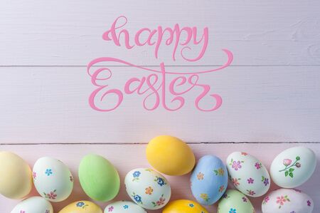 Easter colorful eggs and flowers, holiday background for your decoration. Egg hunt, copy space, "Happy Easter" hand draw letteringの写真素材
