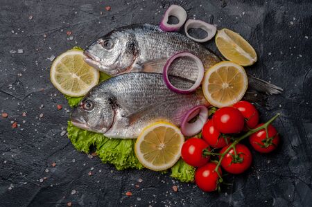 Fresh dorado fishes on bord prepared to cooking, vegetables and fresh sea food. Cooking background, flat layの写真素材