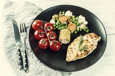 Fried chicken fillet and boiled vegetables, delicious barbecue dinner, flat lay food background. Vintage stylization, retro film filterの写真素材
