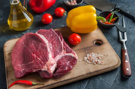 Beef steaks ready to cooking on culinary background. Fresh raw meat on wooden cutting board with rosemary, selective focusの写真素材