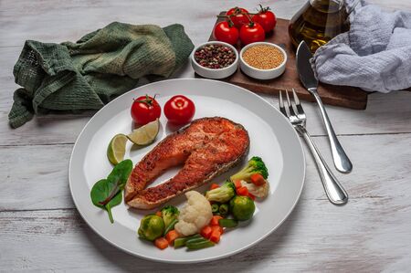 Fried salmon fishes and boiled vegetables on plate, cooking delicious and healthy, fresh sea food. Cooking background, selective focusの写真素材