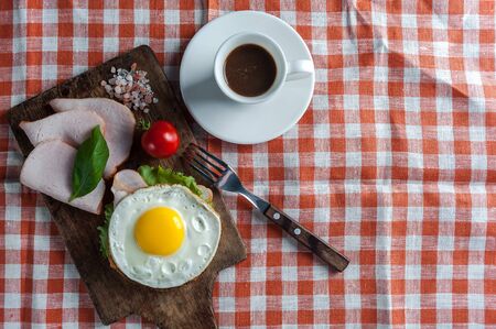 Breakfast with fried egg on sandwich and coffee on wooden table. Morning food, flat layの写真素材