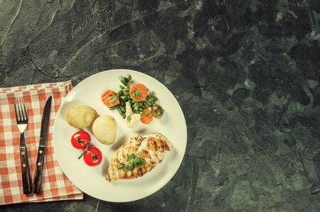 Fried chicken fillet and boiled vegetables, delicious barbecue dinner, flat lay food background. Retro film filter, vintag stylizationの写真素材