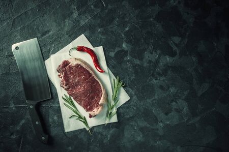 Beef steaks rib eye ready to cooking, culinary background. Fresh raw meat on wooden cutting board with rosemary, flat lay. Retro film filter, vintag stylizationの写真素材