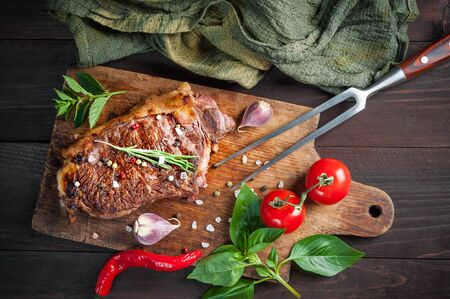 Beef steaks rib eye fried on grille, culinary background. Grilled meat on wooden cutting board with rosemary, flat layの写真素材