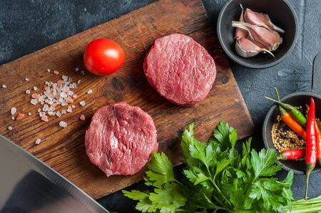 Beef steaks fillet mignon ready to cooking on culinary background and spicy. Fresh raw meat on wooden cutting board with rosemary, selective focusの写真素材