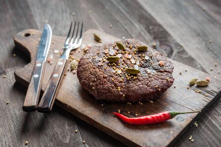 Beef steaks rib eye fried on grille, culinary background. Grilled meat on wooden cutting board with rosemary, flat layの写真素材