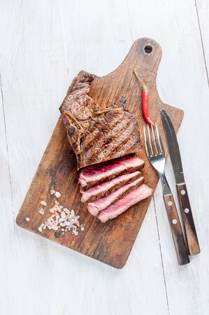 Beef steaks rib eye fried on grille, culinary background. Grilled meat on wooden cutting board with rosemary, flat layの写真素材
