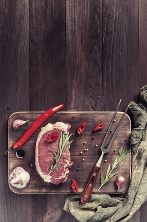 Beef steaks rib eye ready to cooking, culinary background. Fresh raw meat on wooden cutting board with rosemary, flat lay. Retro film filter, vintage stylizationの写真素材
