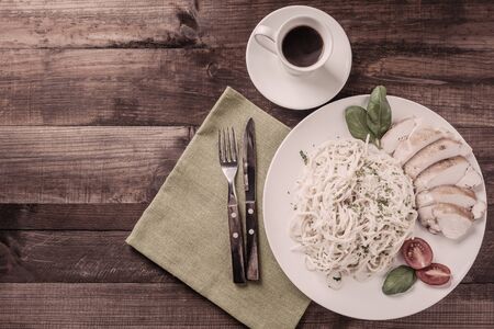 Italian spaghetti pasta with sauce and chicken, cheese parmesan and basil. Food background, flat lay. Vintage stylization, retro film filterの写真素材