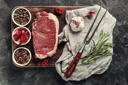Beef steaks rib eye ready to cooking, culinary background. Fresh raw meat on wooden cutting board with rosemary, flat lay. Vintage stylization, retro film filterの写真素材