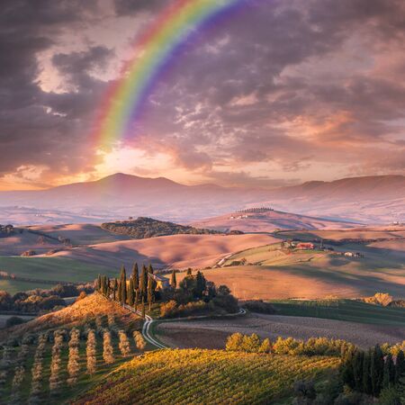 Summer landscape with rainbow over bright vineyards and gardens on hills, farmland view, Tuscanyの写真素材