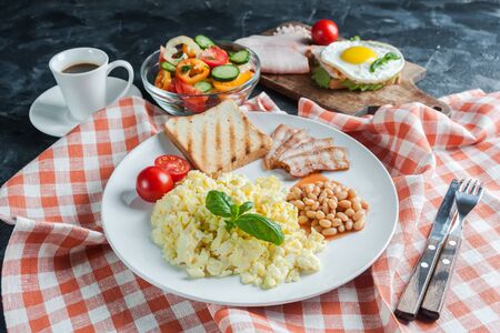 Breakfast with scrambled eggs and bacon on plate and coffee on wooden table. Morning food, selective focusの写真素材
