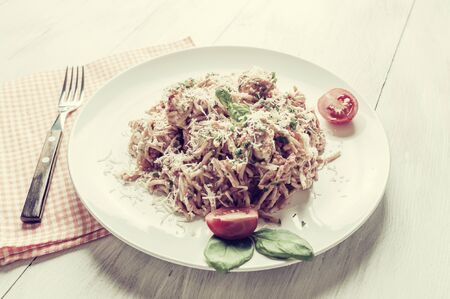 Italian spaghetti pasta with sauce and chicken, cheese parmesan and basil. Food background, selective focus. Vintage stylization, retro film filterの写真素材