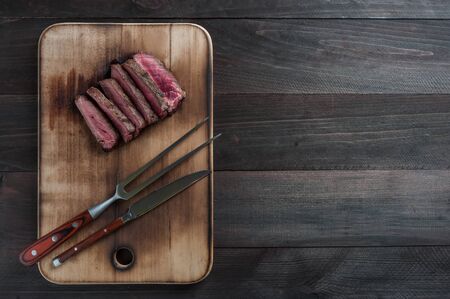 Beef steaks rib eye fried on grille, culinary background. Grilled meat on wooden cutting board with rosemary, flat layの写真素材