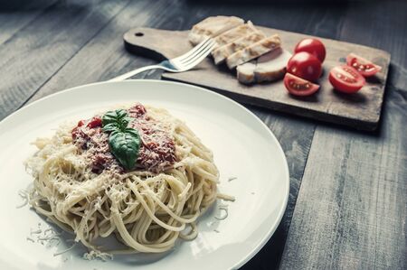 Italian spaghetti pasta with sauce and chicken, cheese parmesan and basil. Food background, flat lay. Vintage stylization, retro film filterの写真素材