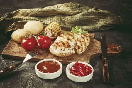 Fried chicken fillet and boiled vegetables, delicious barbecue dinner, flat lay food background. Vintage stylization, retro film filterの写真素材