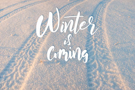 Tire tracks on the snow and hand lettering text winter is comingの写真素材