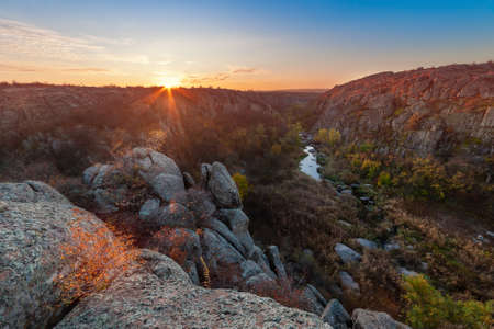 Autumn morning landscape with fall river in canyon and sun in skyの写真素材