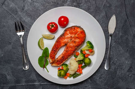 Fried salmon fishes and vegetables on plate, cooking delicious and healthy, fresh sea food. Cooking background, flat layの写真素材