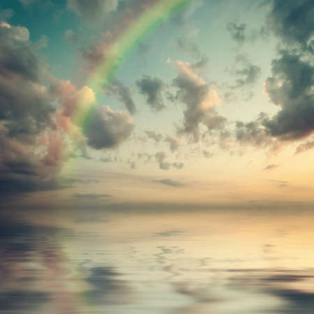 Beautiful nature background - majestic sky with clouds and rainbow reflection in water. Vintage stylization, retro film filterの写真素材