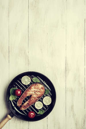 Fried salmon fishes in pan, cooking delicious and healthy, fresh sea food. Cooking background, flat lay. Vintage stylization, retro film filterの写真素材