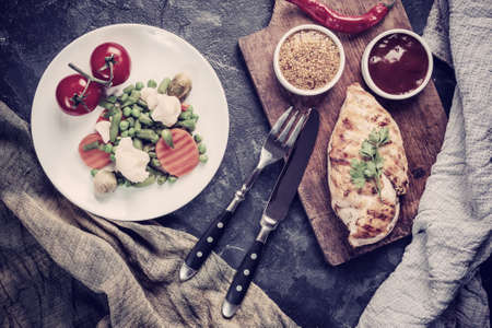 Fried chicken fillet and boiled vegetables, delicious barbecue dinner, flat lay food background. Vintage stylization, retro film filterの写真素材