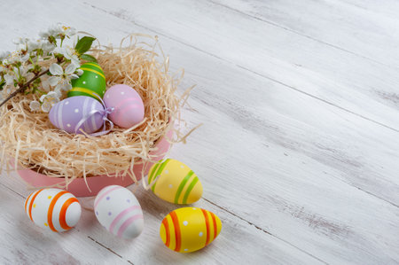 Happy easter card with painted eggs and flowers on colorful table, holiday background for your card. Egg hunt, copy spaceの写真素材