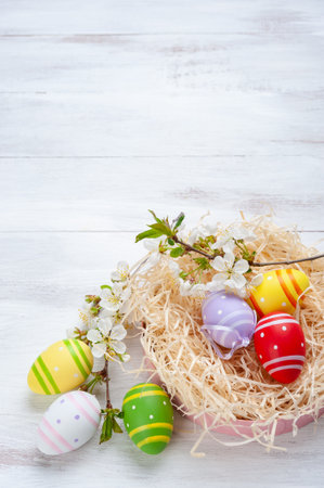 Happy easter painted eggs with flowers on wooden colorful table, holiday background for your card. Egg hunt, copy spaceの写真素材