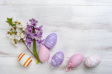 Happy easter card with painted eggs and flowers on colorful table, holiday background for your card. Egg hunt, copy spaceの写真素材