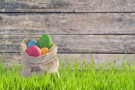 Easter card with eggs in bag and grass, wooden backdropの写真素材