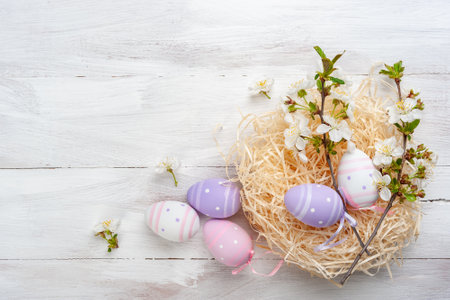 Happy easter card with painted eggs and flowers on colorful table, holiday background for your card. Egg hunt, copy spaceの写真素材