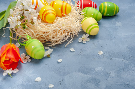 Happy easter card with painted eggs and flowers on colorful table, holiday background for your card. Egg hunt, copy spaceの写真素材