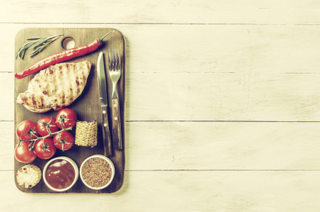 Fried chicken fillet and boiled vegetables, delicious barbecue dinner, flat lay food background. Retro stylization, vintage film filterの写真素材