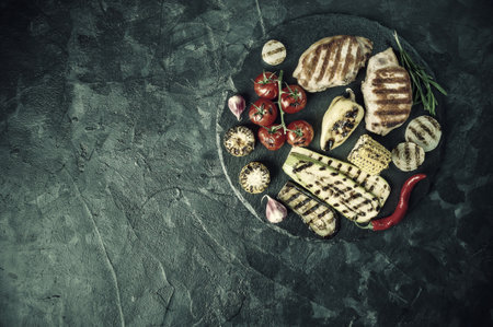Fried pork fillet and grilled vegetables, delicious barbecue dinner, flat lay food background. Retro stylization, vintage film filterの写真素材
