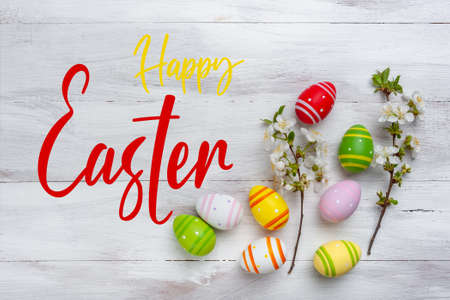 Easter painted eggs and blooming branches on wooden rustic table with hand lettering text, holiday background.の写真素材