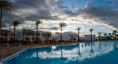 Summer vacation on ocean shore with swimming pool, palms and mountains, warm sand and seaの写真素材