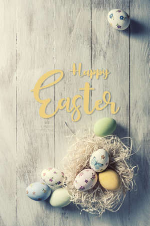 Easter painted eggs on wooden rustic table with hand lettering text, holiday background for your. Retro film filter, vintage stylizationの写真素材