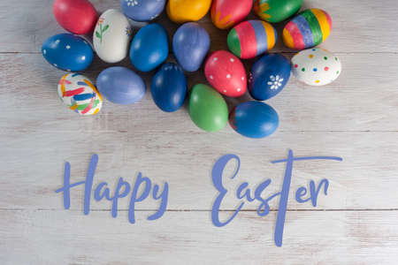 Easter painted eggs and blooming branches on wooden rustic table with hand lettering text, holiday background.の写真素材