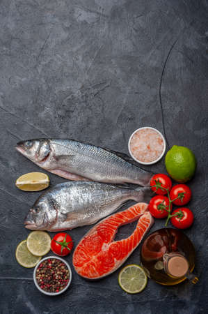 Fresh salmon, dorado and seabass fishes on bord prepared to cooking, vegetables and fresh sea food. Flat layの写真素材