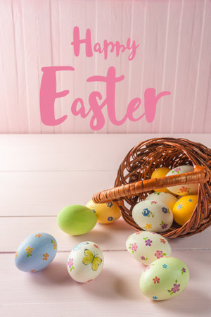 Happy easter painted eggs in basket on wooden table and hand lettering textの写真素材