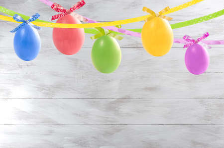 Holiday card with colorful easter eggs hang on ribbon and place for your textの写真素材