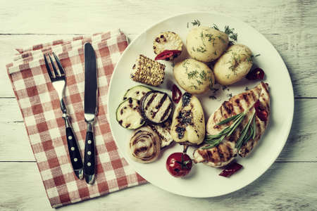Chicken fried fillet and grilled vegetables, delicious barbecue dinner, flat lay food background; Retro stylization, vintage film filterの写真素材