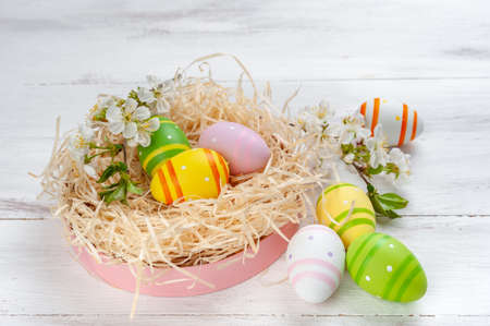 Easter holiday card with colorful eggs and flowers on wooden background, place for your text