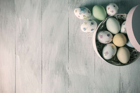 Happy easter painted eggs on wooden table, holiday background for your decoration. Retro film filter, vintage stylizationの写真素材