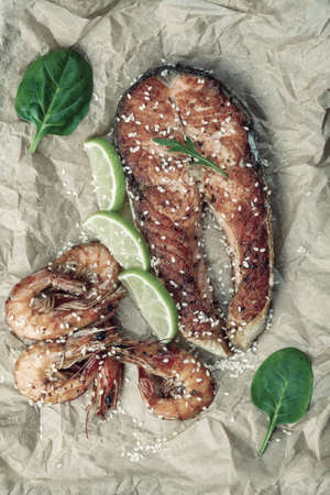 Fried salmon fishes and shrimps on paper, cooking delicious and healthy, fresh sea food. Cooking background, flat lay. Retro stylization, vintage film filterの写真素材