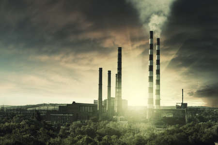 Vintage industrial landscape with smoke from pipes in old factory on sunset, ecology catastrophe and climate change. Retro film filterの写真素材
